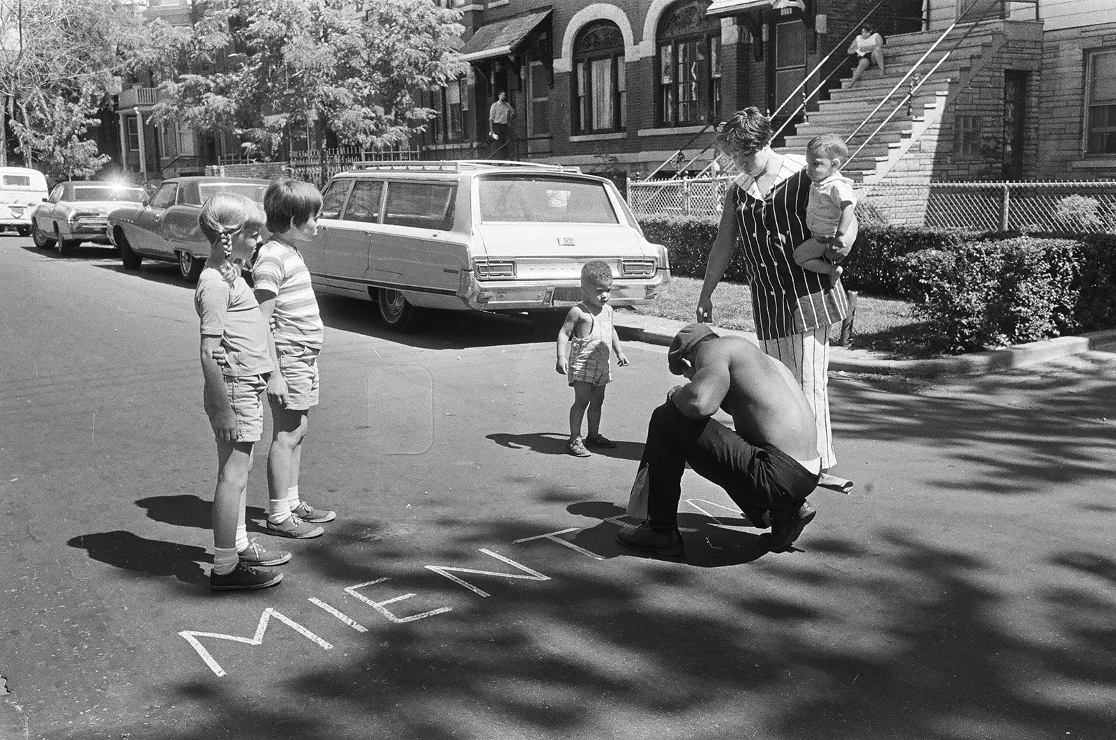 Black and white photograph of a person writing on the street with chalk